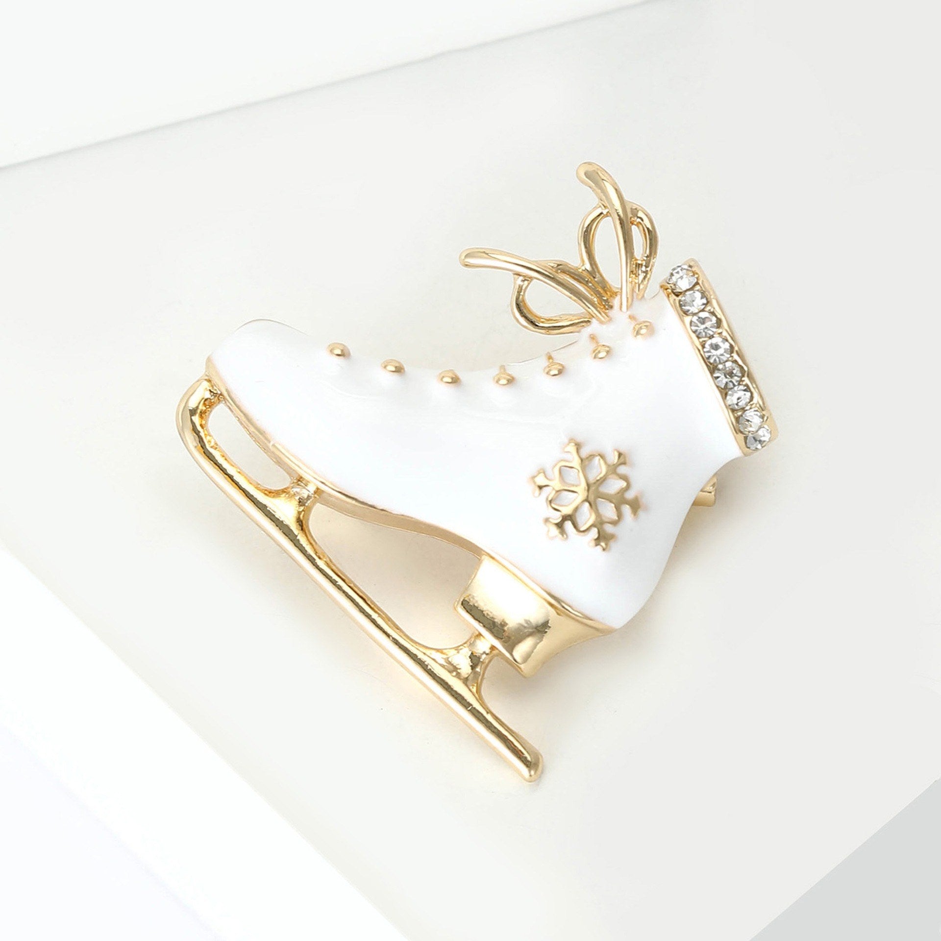 Vintage Schlittschuhbrosche Weiß-Gold – Schrägansicht weißer Hintergrund