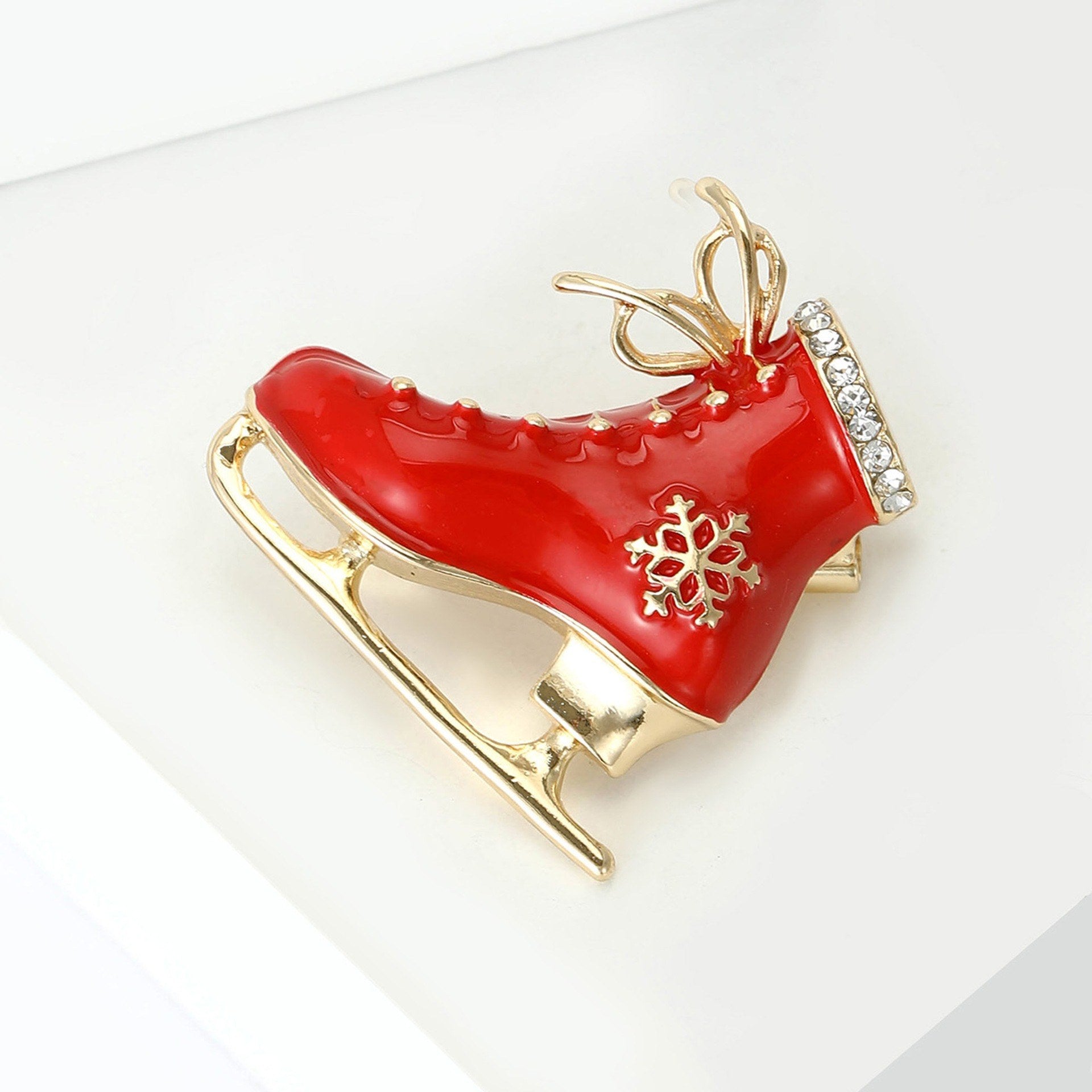 Vintage Schlittschuhbrosche Rot-Gold – Frontansicht schwarzer Hintergrund